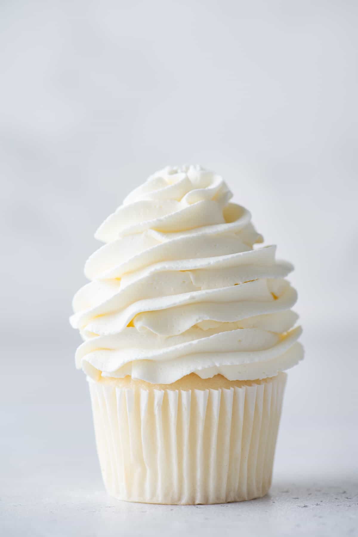 stabilized whipped cream piped on top of a vanilla cupcake