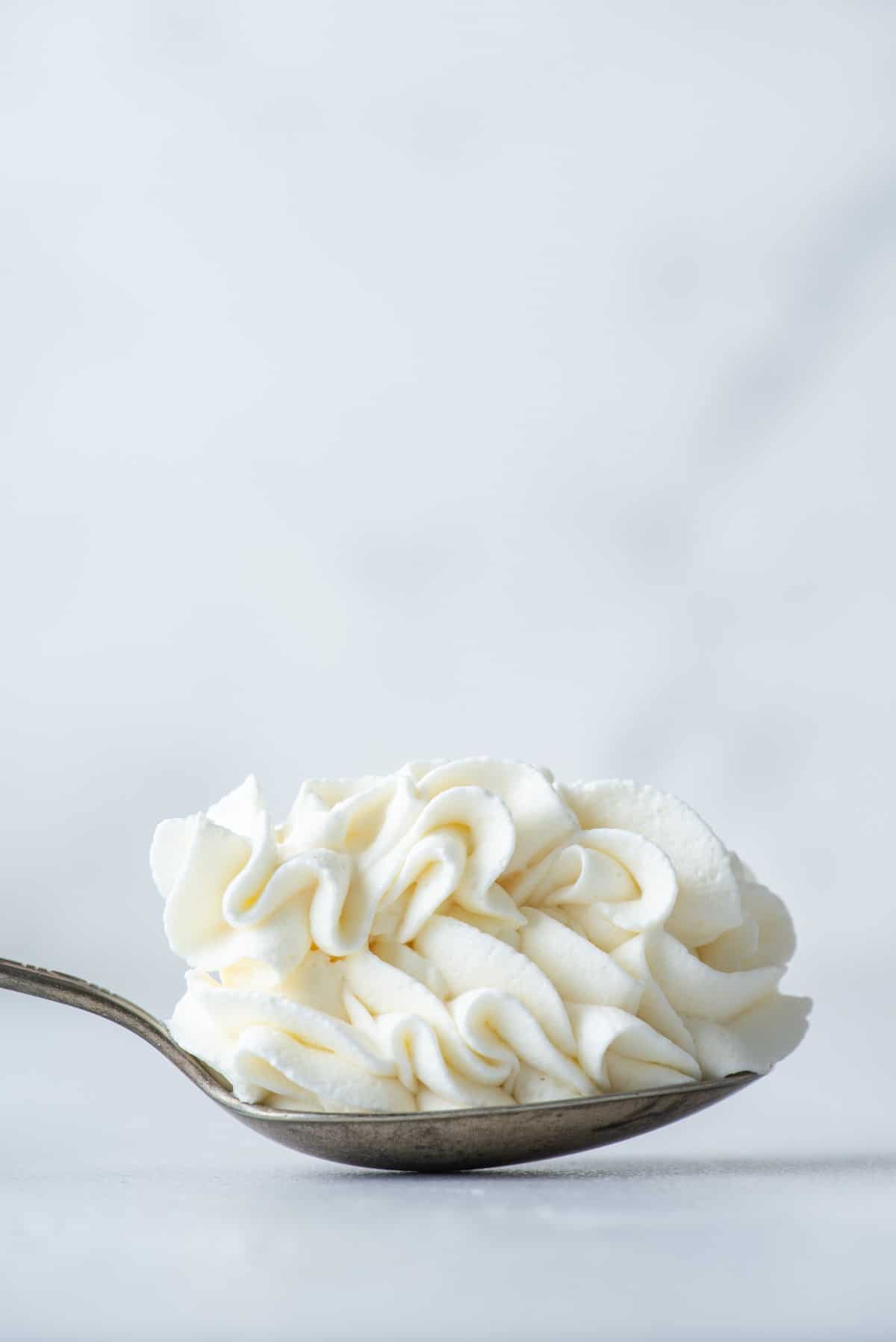 a spoon full of stabilized whipped cream laying on a flat surface