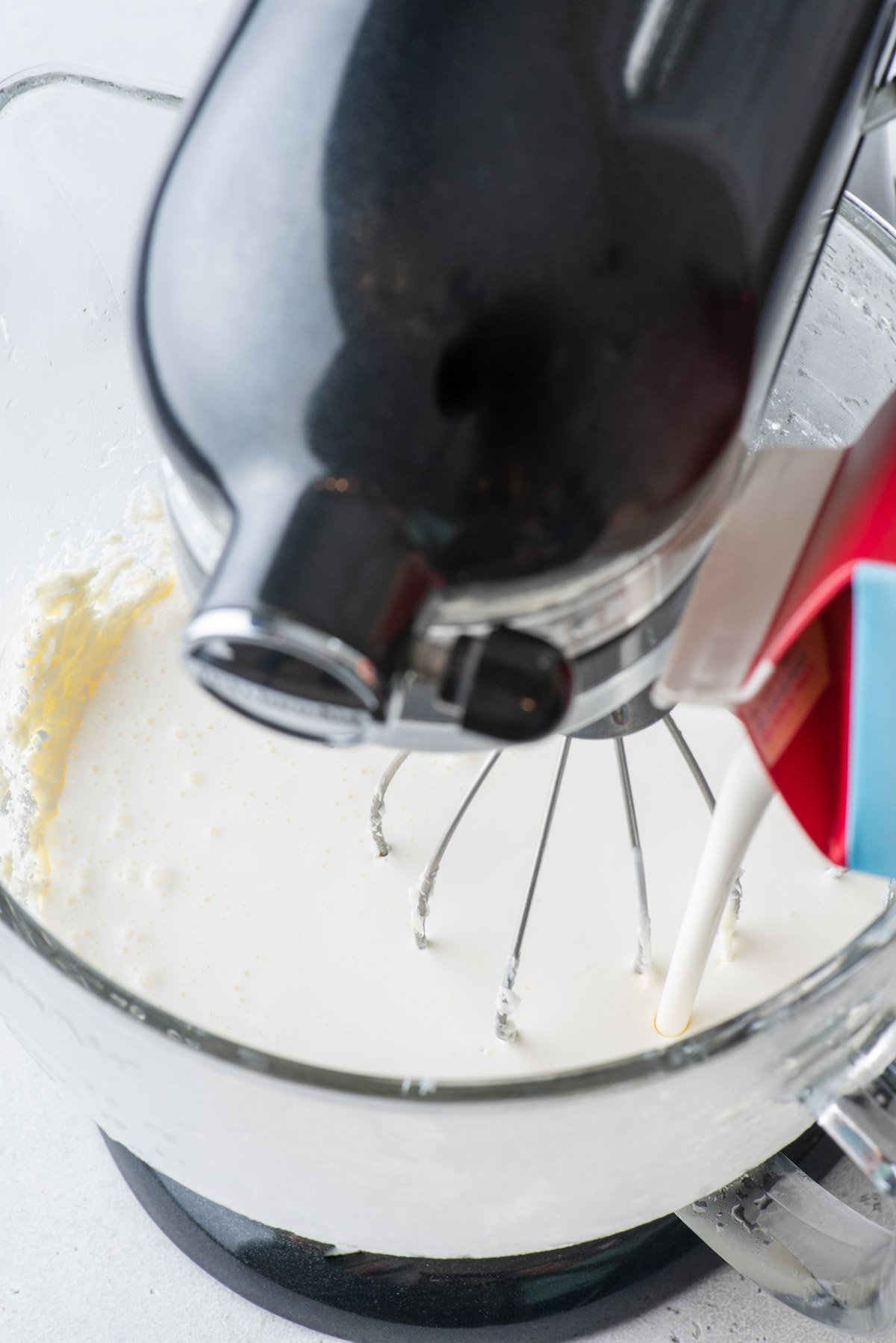 heavy cream being added to an electric mixer with other ingredients