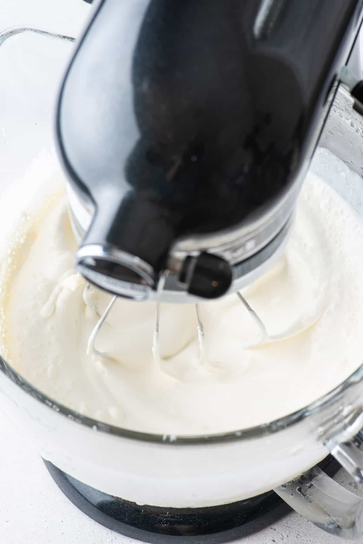 ingredients for stabilized whipped cream being mixed in an electric mixer