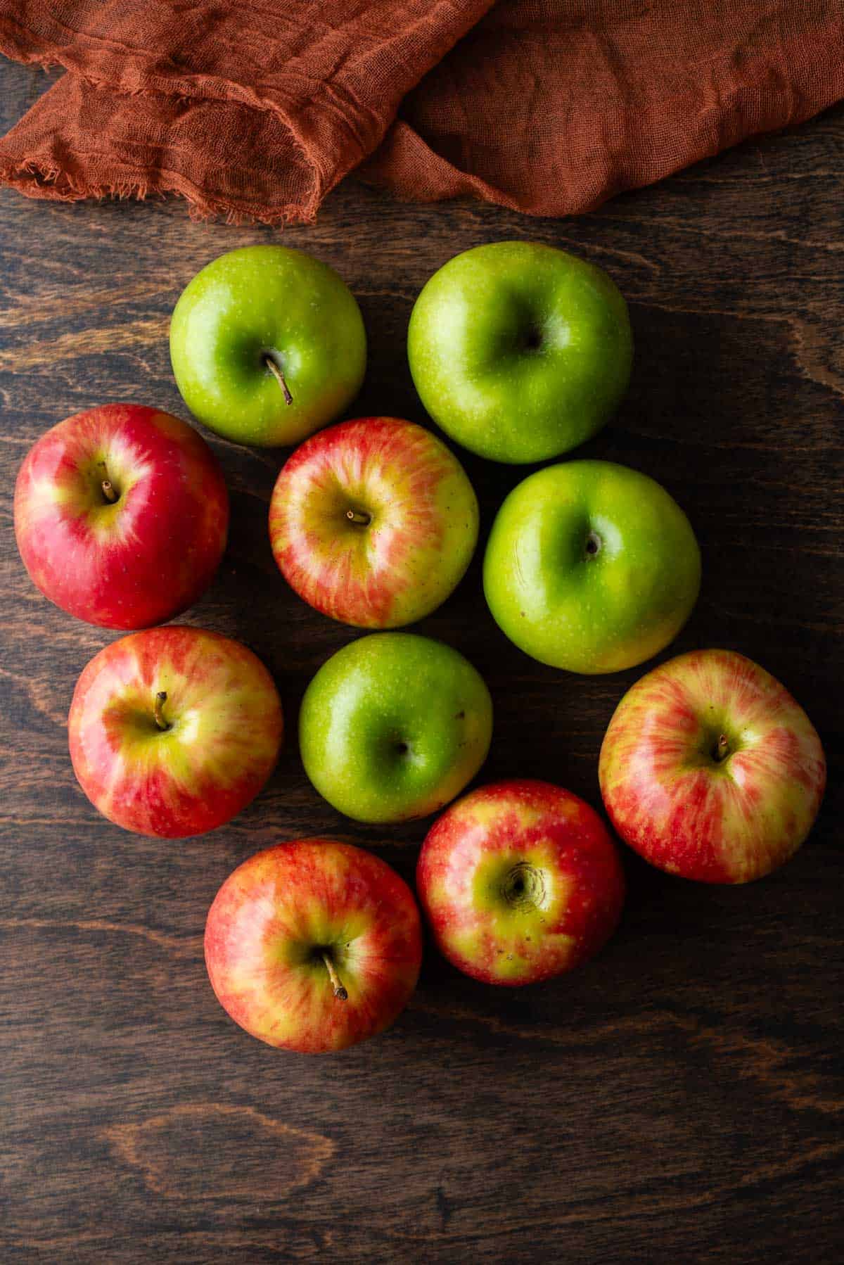 an assortment of different types of apples on a wood surface