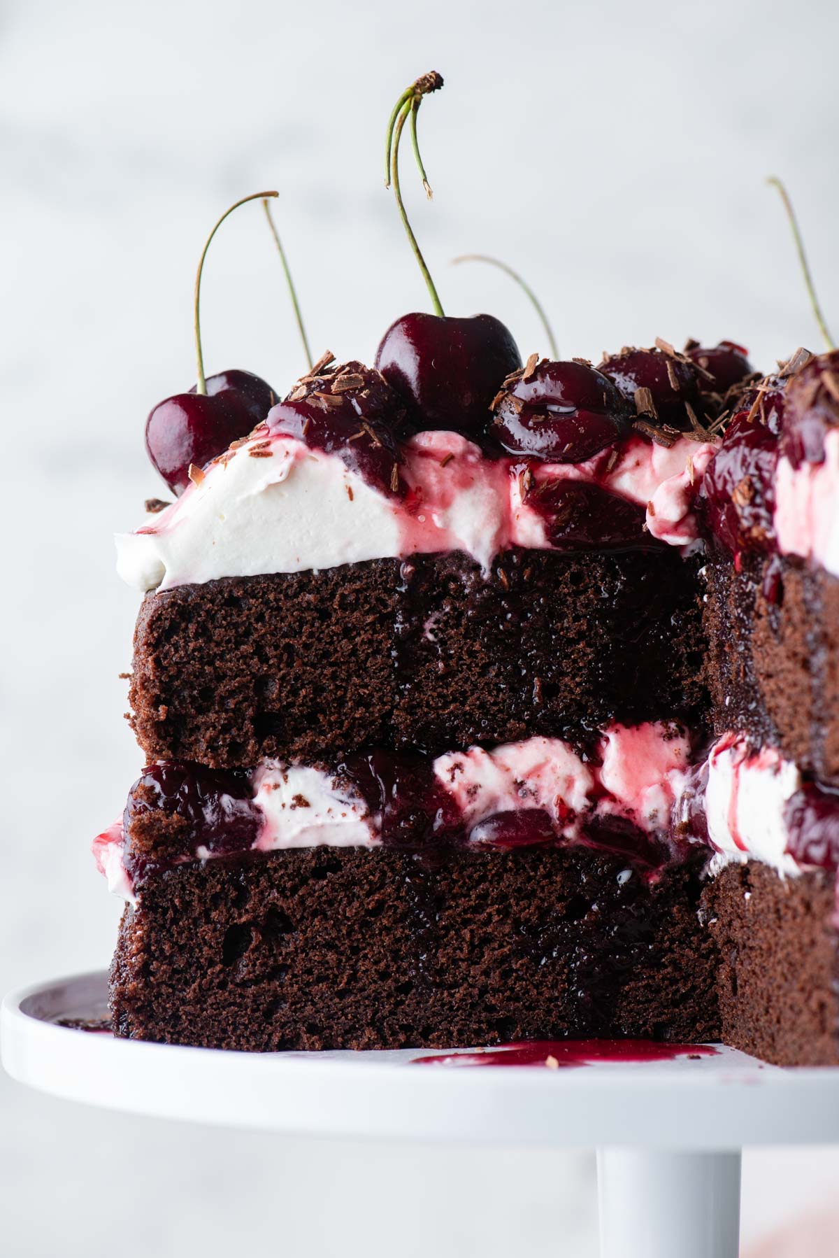 close up of a black forest cake with a large slice cut out, showing the layers of cake, whipped cream and cherry filling