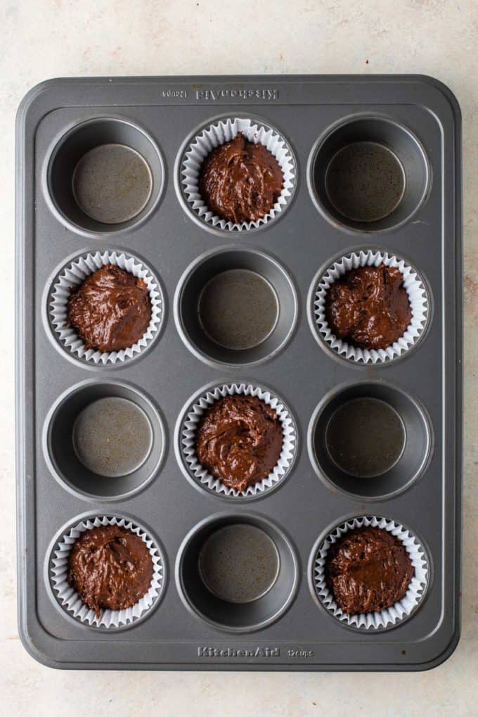 chocolate muffin batter in the bottom of muffin papers in every other hole of a muffin pan