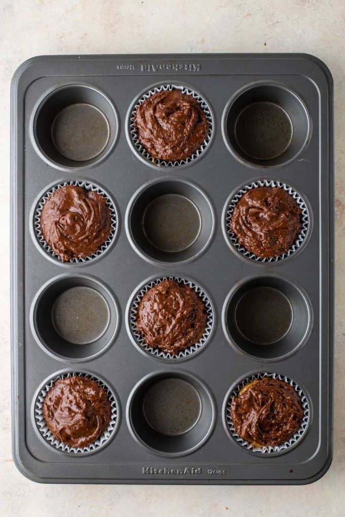 chocolate muffin batter in muffin liners in every other whole of a muffin pan