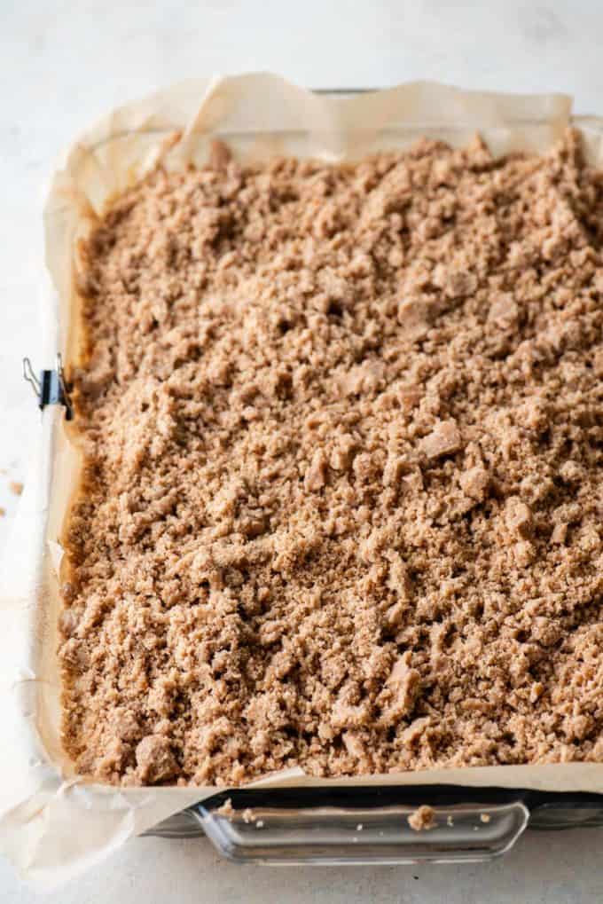 coffee cake batter with crumb topping in a baking pan lined with parchment paper