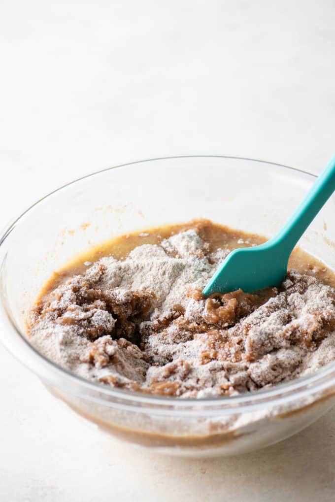 coffee cake crumb topping ingredients being mixed in a clear glass bowl with a teal spatula