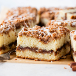 square slices of coffee cake with a fork and cinnamon stick