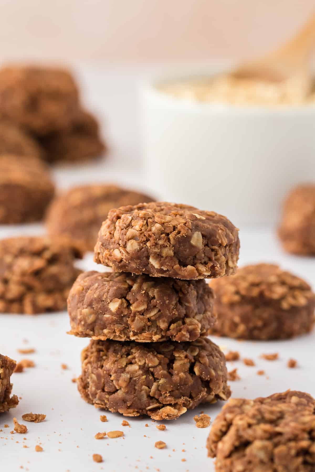 a stack of 3 no bake cookies with more cookies scattered behind them