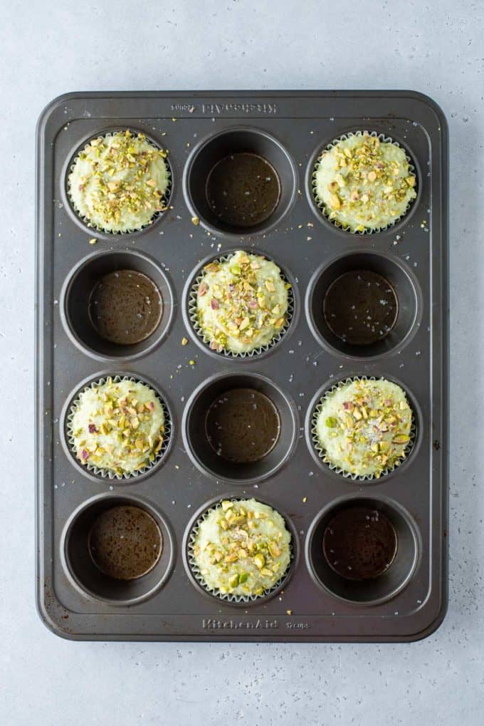 pistachio muffin batter filled in every other hole of a muffin tin