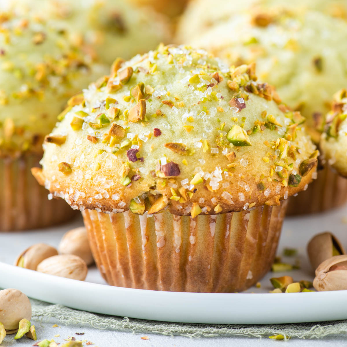 pistachio muffins surrounded by whole pistachios in shells