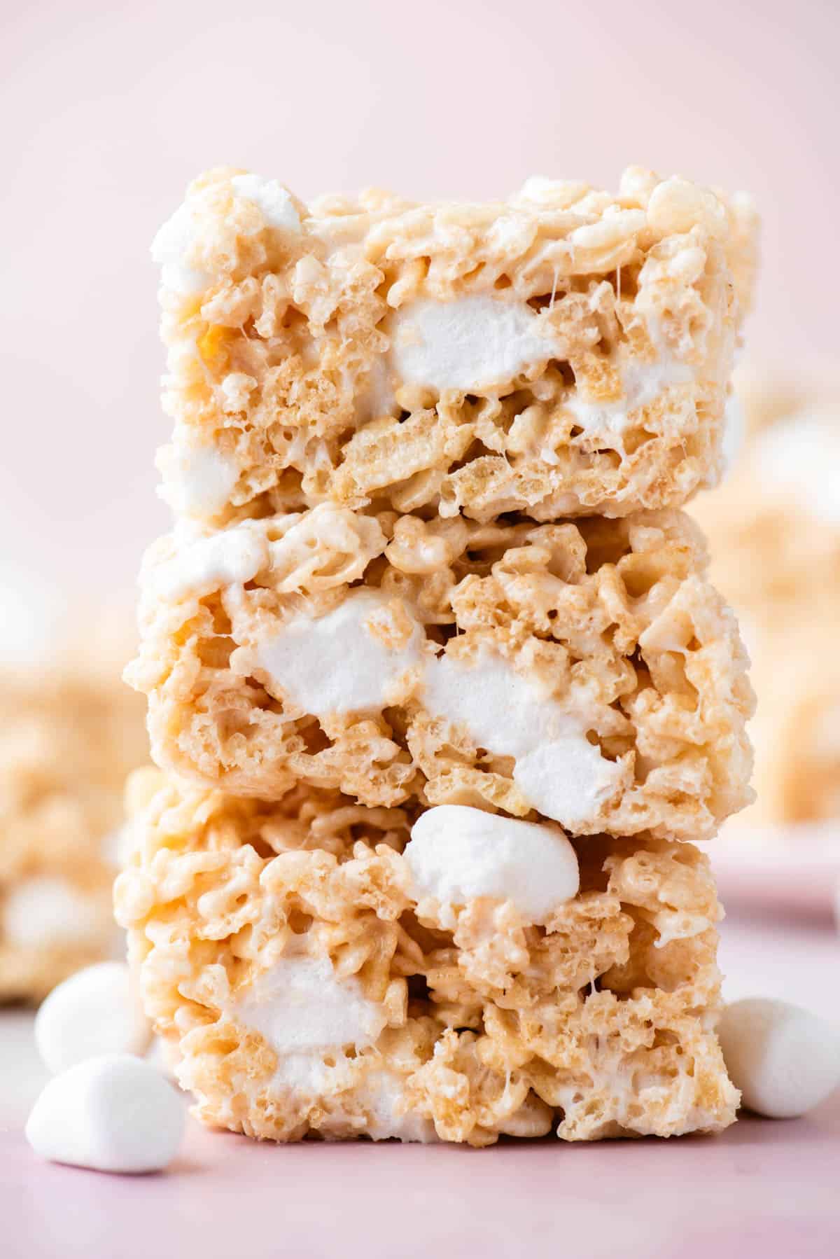 a stack of three rice krispie treat squares with mini marshmallows sprinkled around