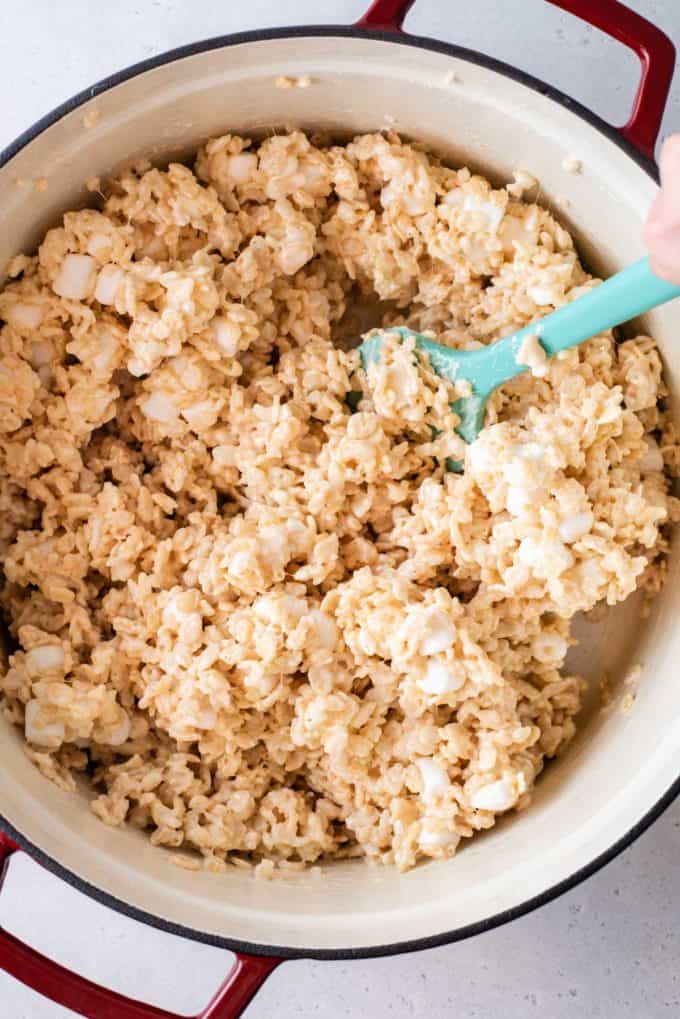 rice krispie treats mixture mixed up in a pot with a teal spatula