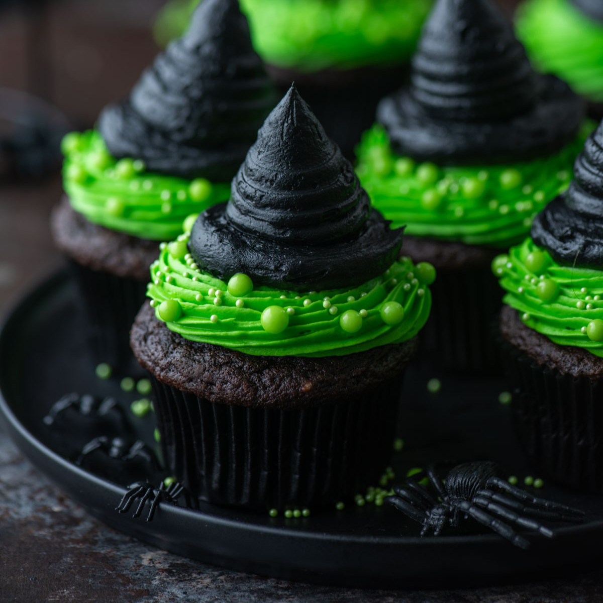 witch hat cup cakes arranged on a black plate