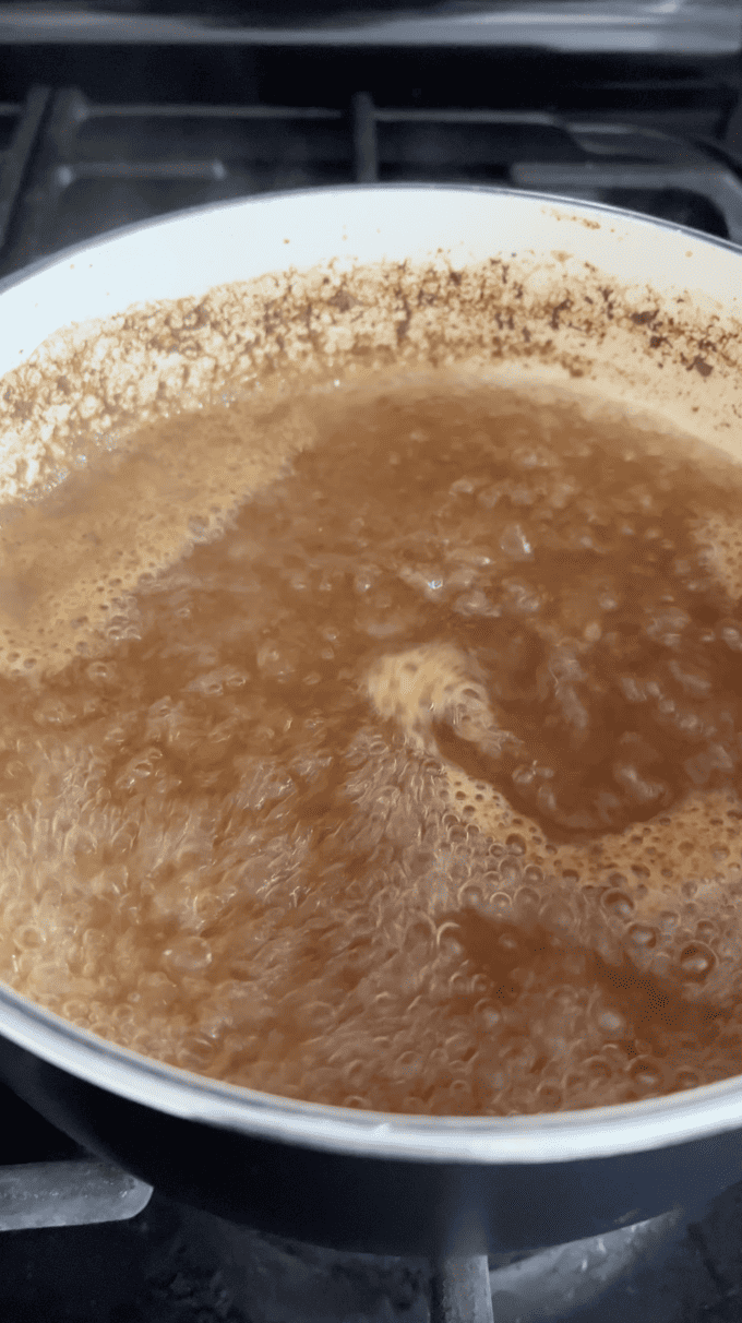 apple cider boiling in a white saucepan