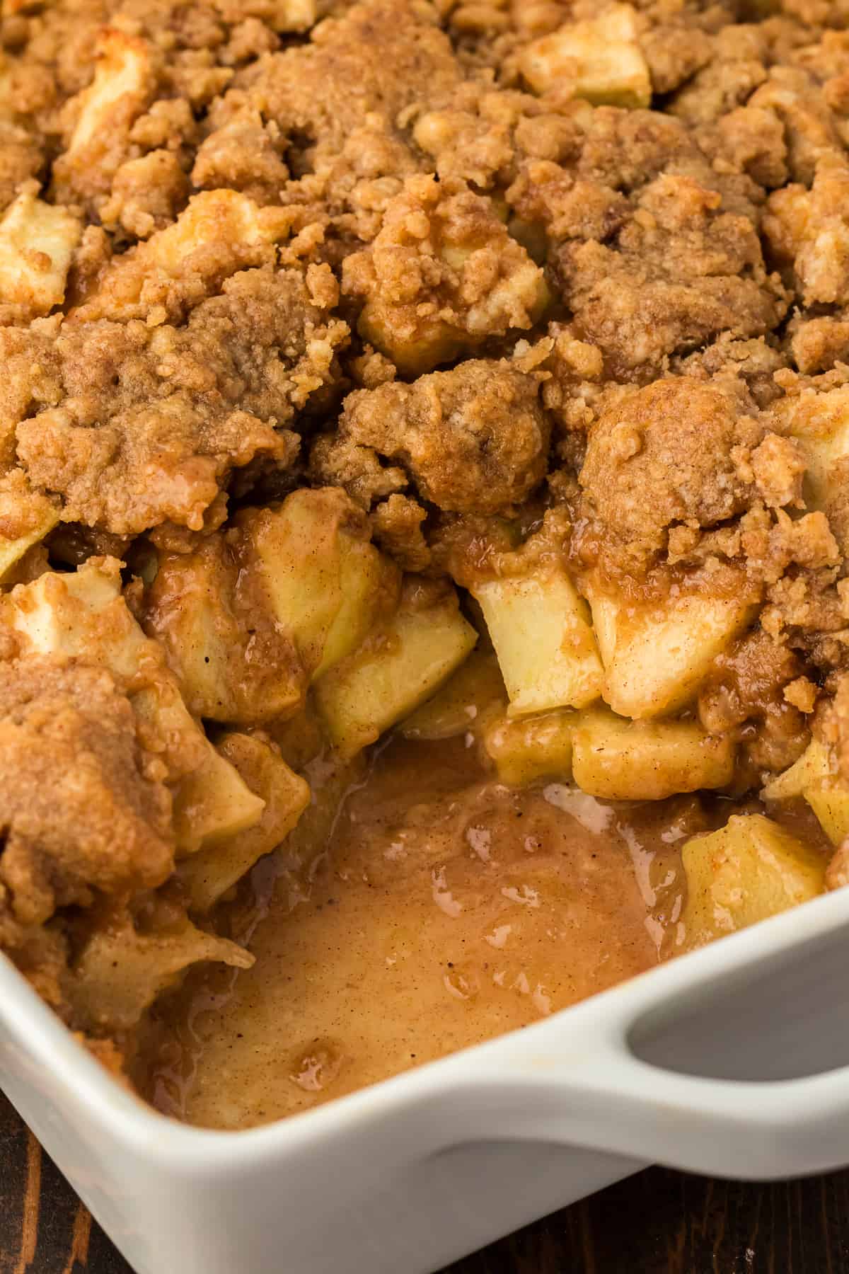 a baking dish of apple crumble with a portion missing out of the corner