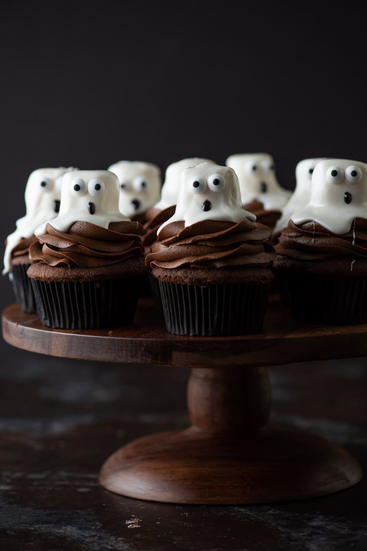 ghost cupcakes on a wooden cake stand