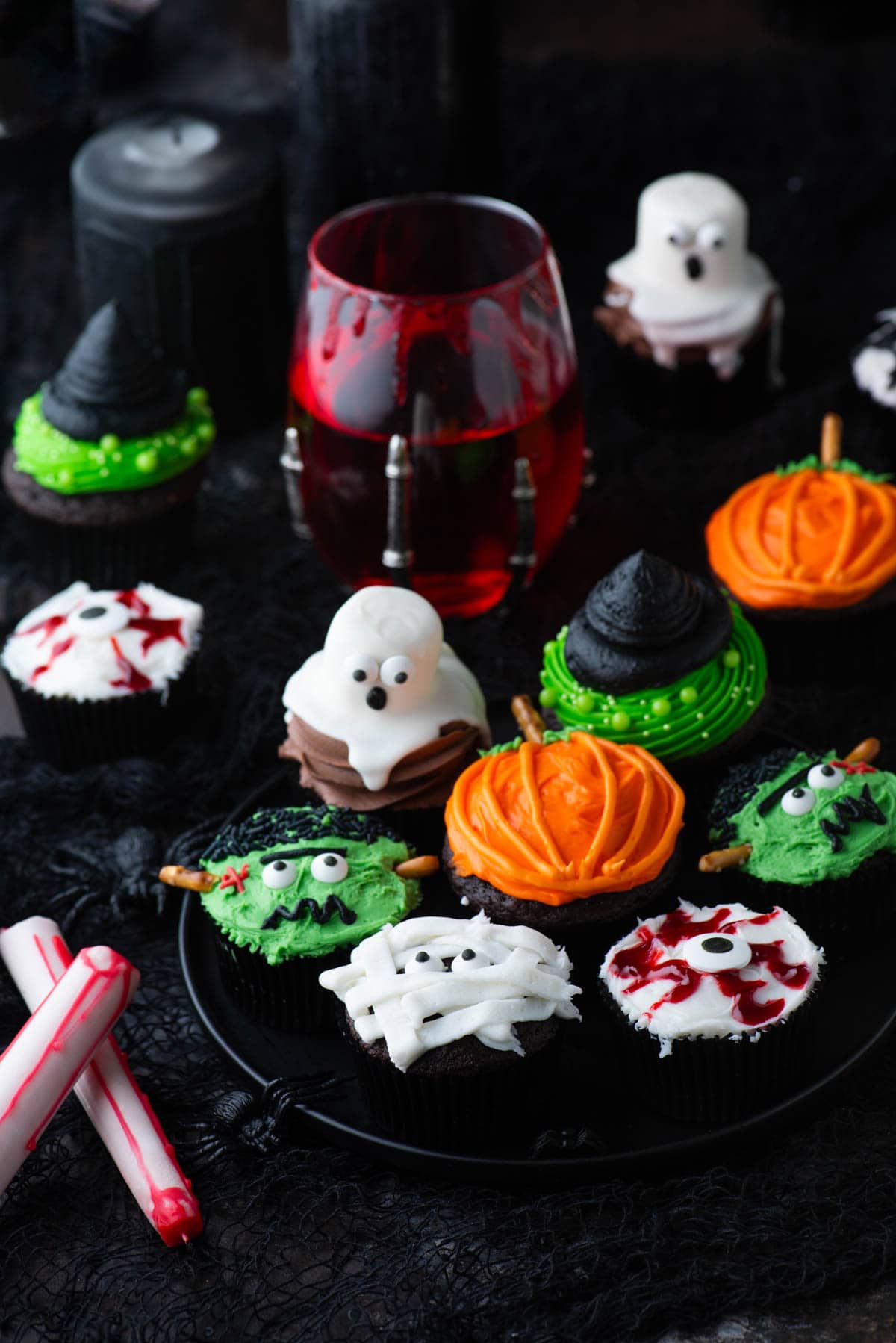assortment of halloween cupcakes including ghost cupcakes, eyeball cupcakes, mummy cupcakes, pumpkin cupcakes, witch hat cupcakes, and spider cupcakes