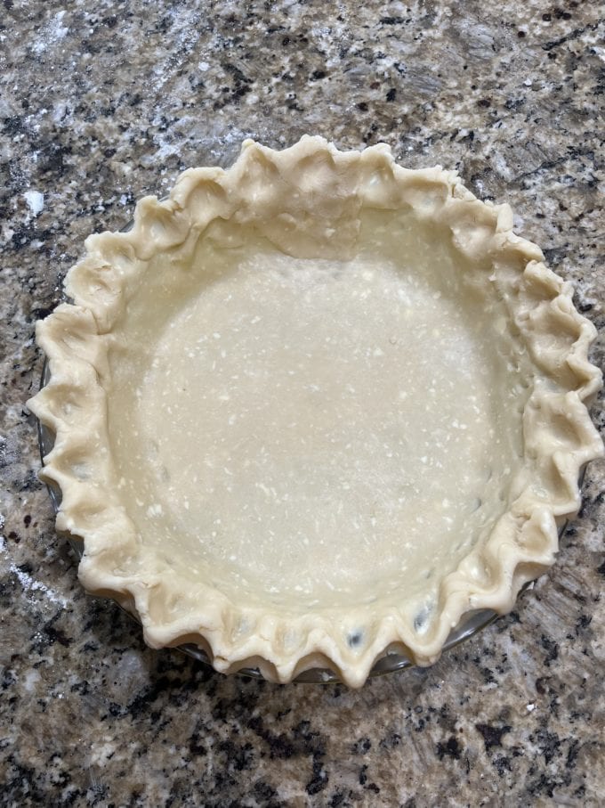 pie crust in a glass pie dish on a granite countertop