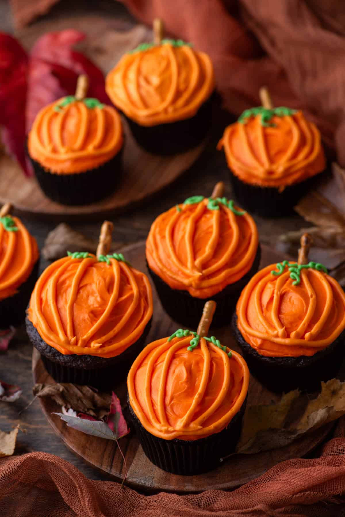 pumpkin patch cupcakes arranged on wood plates with fall leaves around