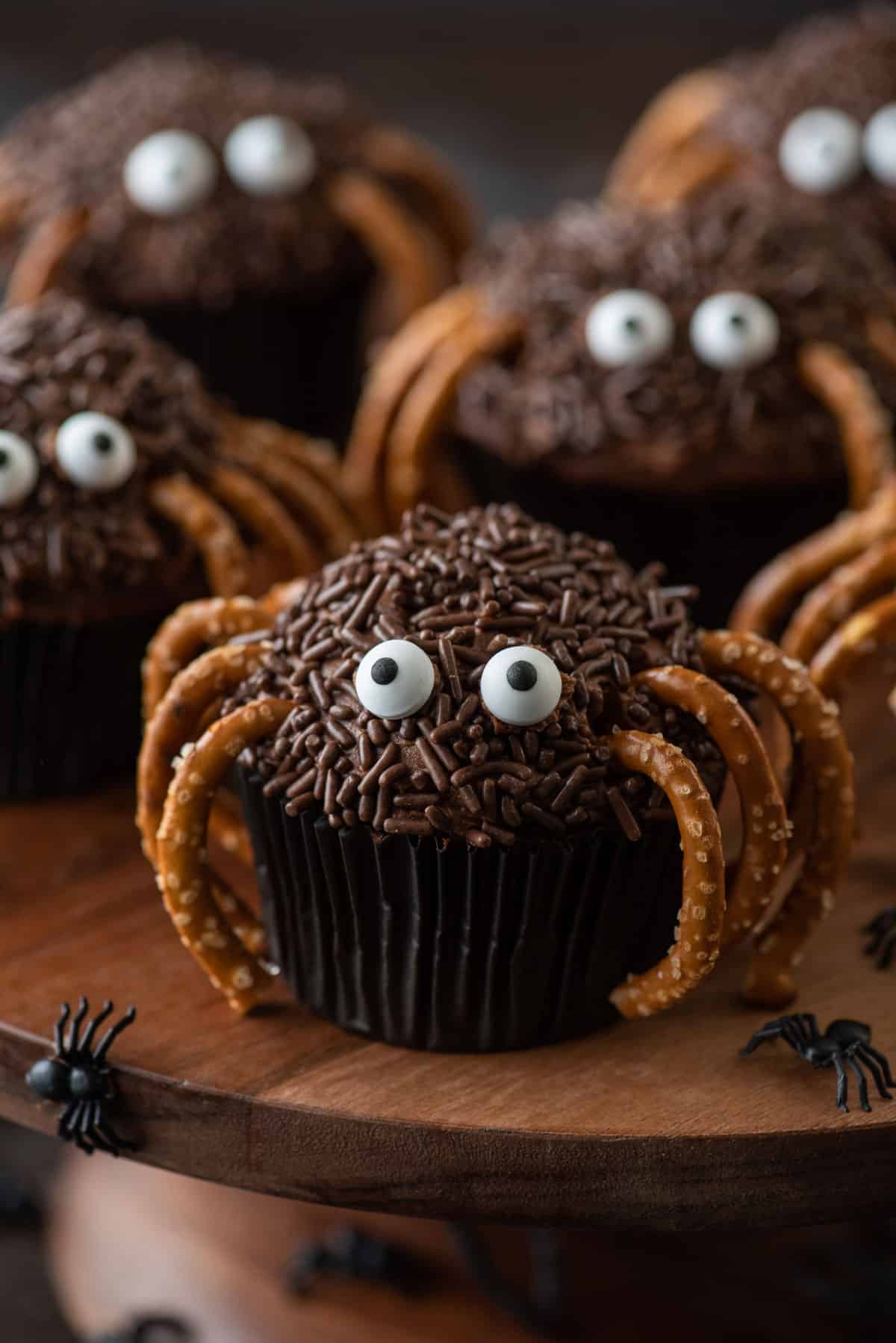spider cupcakes on a wood surface with little black plastic spiders scattered around