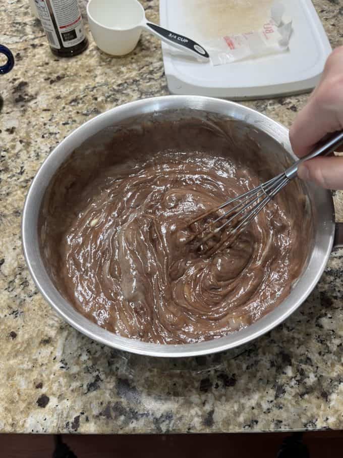 filling for chocolate pie being whisked in a pot sitting on a kitchen counter