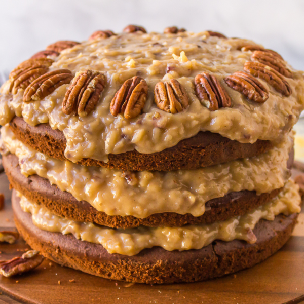 a german chocolate cake on a wood surface topped with a ring of whole pecans