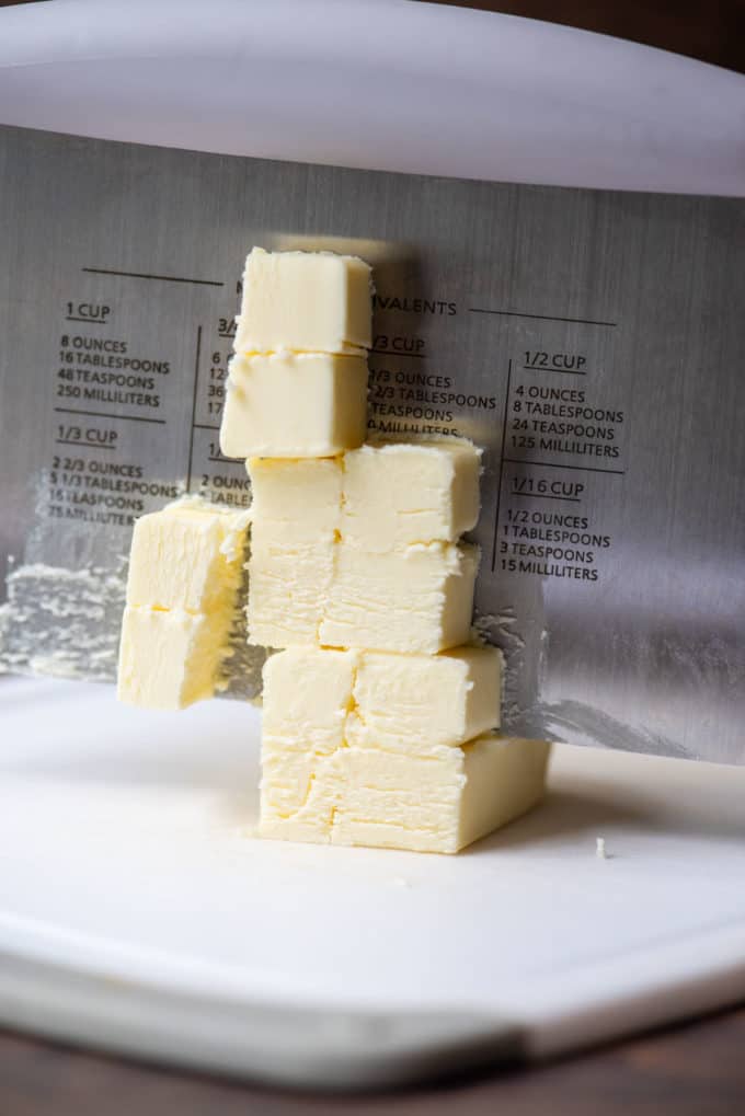 cubes of butter being cut with a pastry cutter on a white cutting board
