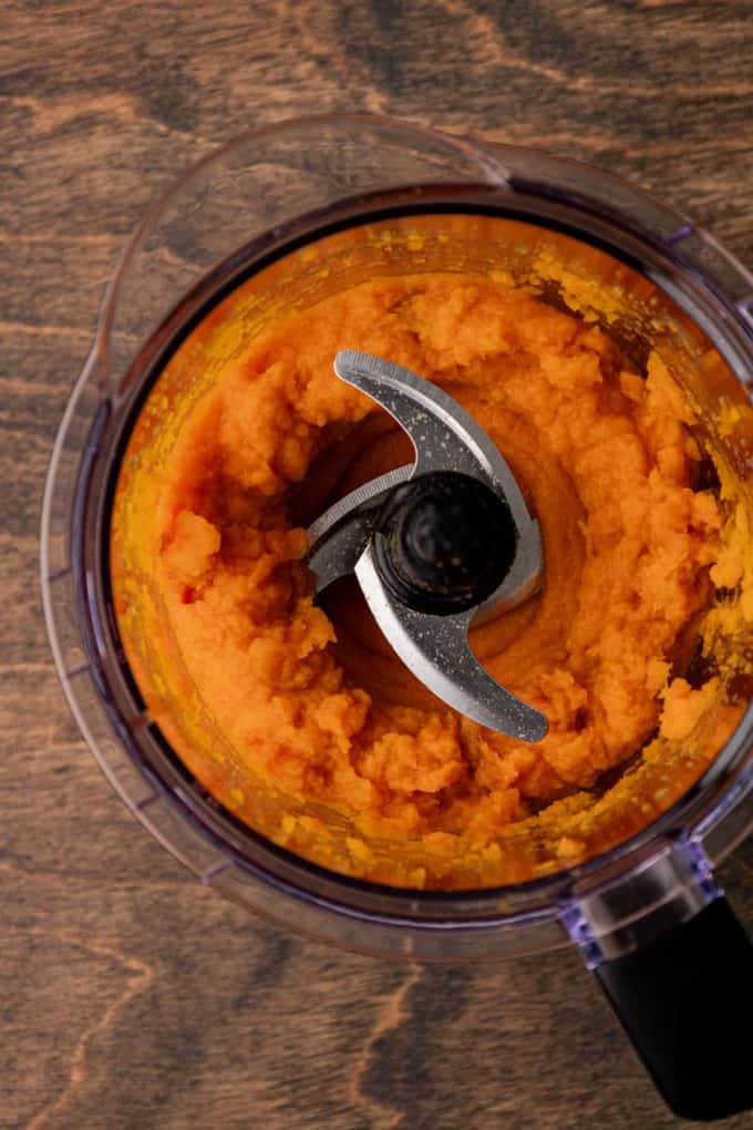 sweet potato that has been mashed in a food processor bowl sitting on a wood surface