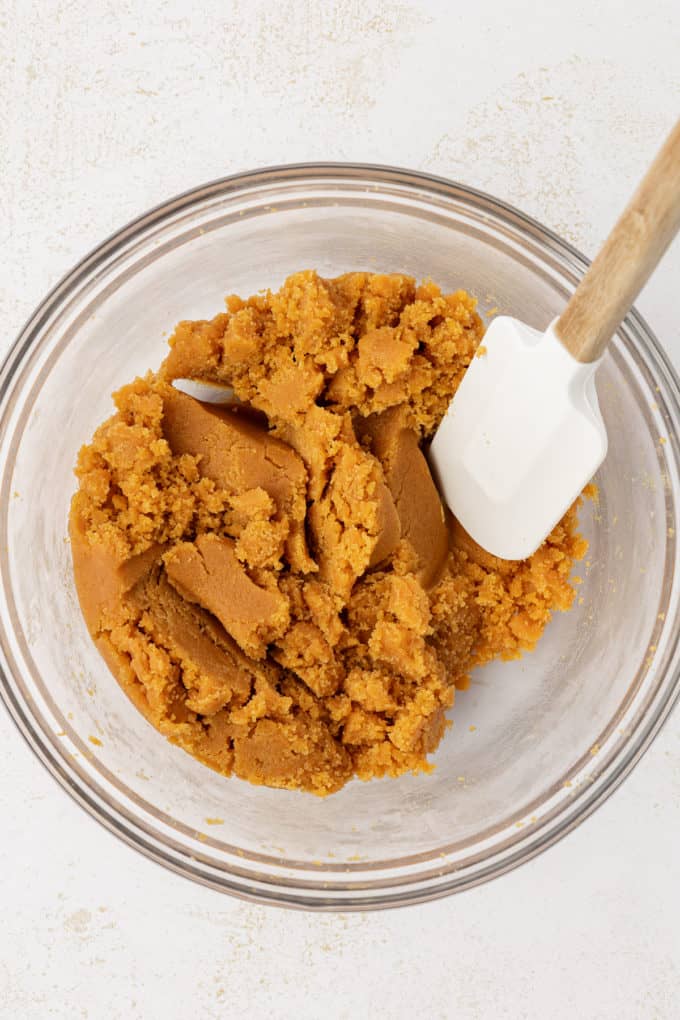 3-ingredient peanut butter cookie dough in a clear glass bowl with a white spatula with a wooden handle