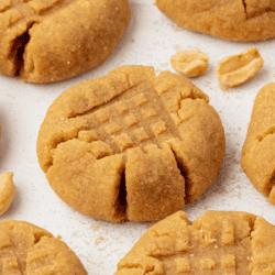 peanut butter cookies on a countertop surface with peanuts scattered around them