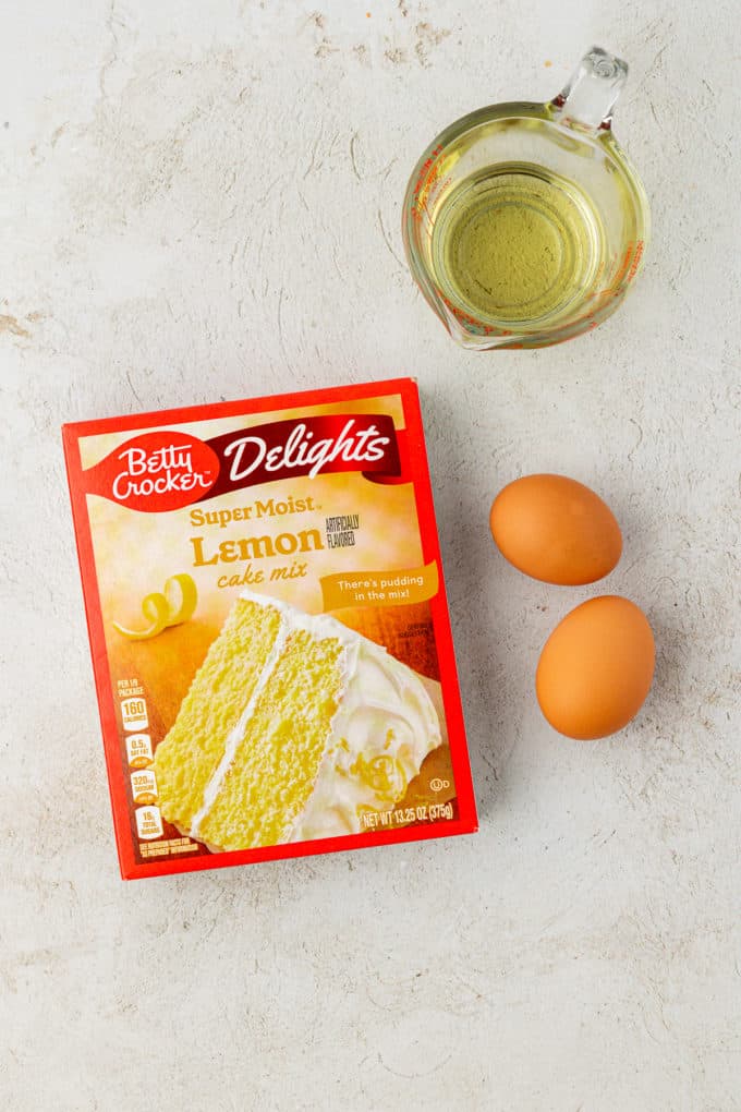 ingredients for lemon cake mix cookies including a box of lemon cake mix, two eggs, and vegetable oil