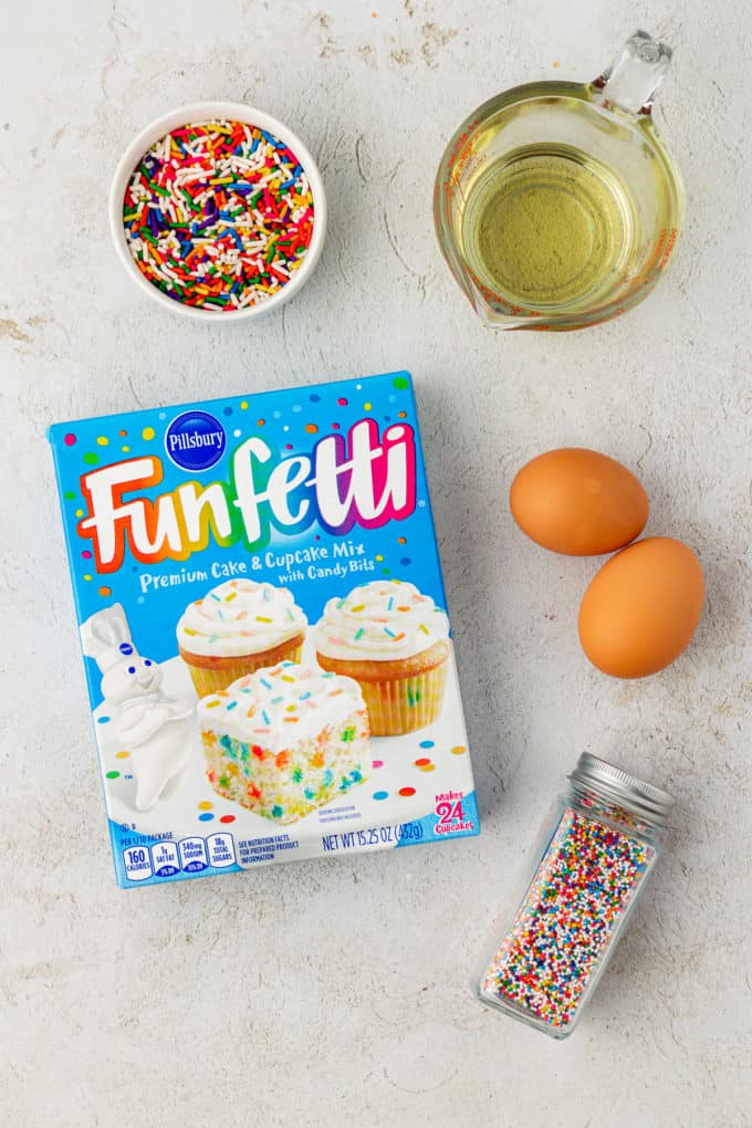 ingredients for funfettie cake mix cookies including a box of funfettie cake mix, two large eggs, sprinkles and vegetable oil