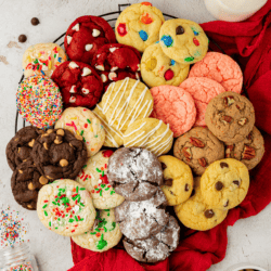 an assortment of cake mix cookies in different flavors in a cirlcle on a wire rack on top of a red towel with sprinkles scattered around
