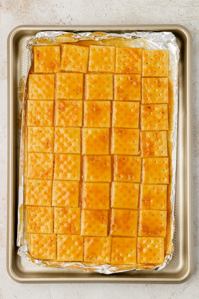 a single layer of saltine crackers on aluminum foil on a sheet pan, covered and cooked with a brown sugar butter mixture over them