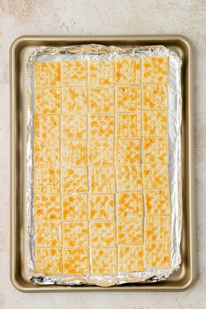 a single layer of saltine crackers covering a sheet pan with aluminum foil on it