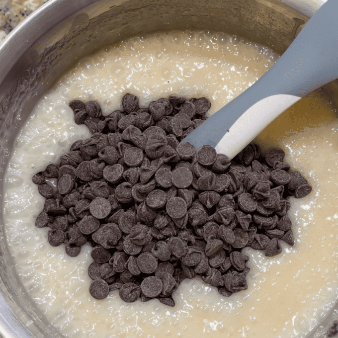 ingredients for fantasy fudge with chocolate chips on top in a pot with a rubber spatula