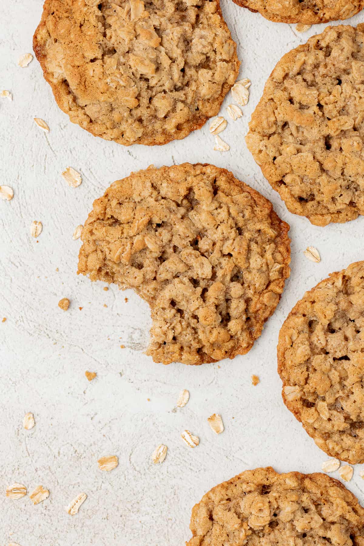 overhead view of oatmeal cookies laying flat with a bite out of one of the cookies and oats sprinkled around
