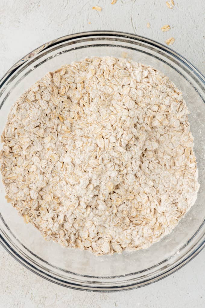 dry ingredients for oatmeal cookies and oats mixed together in a clear glass bowl