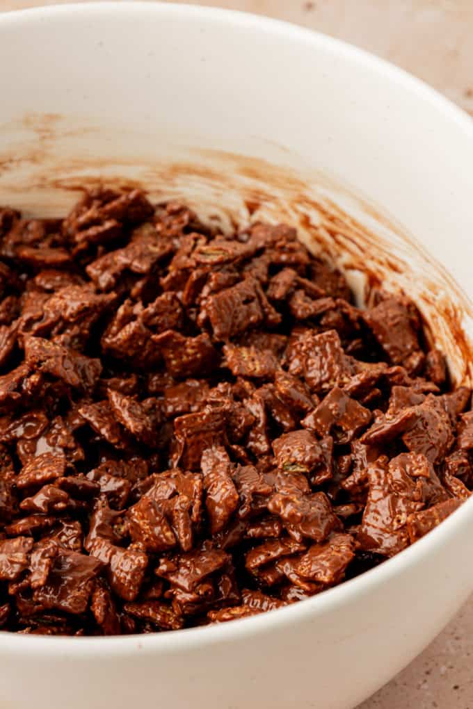 chex cereal coated in a melted chocolate mixture in a white bowl