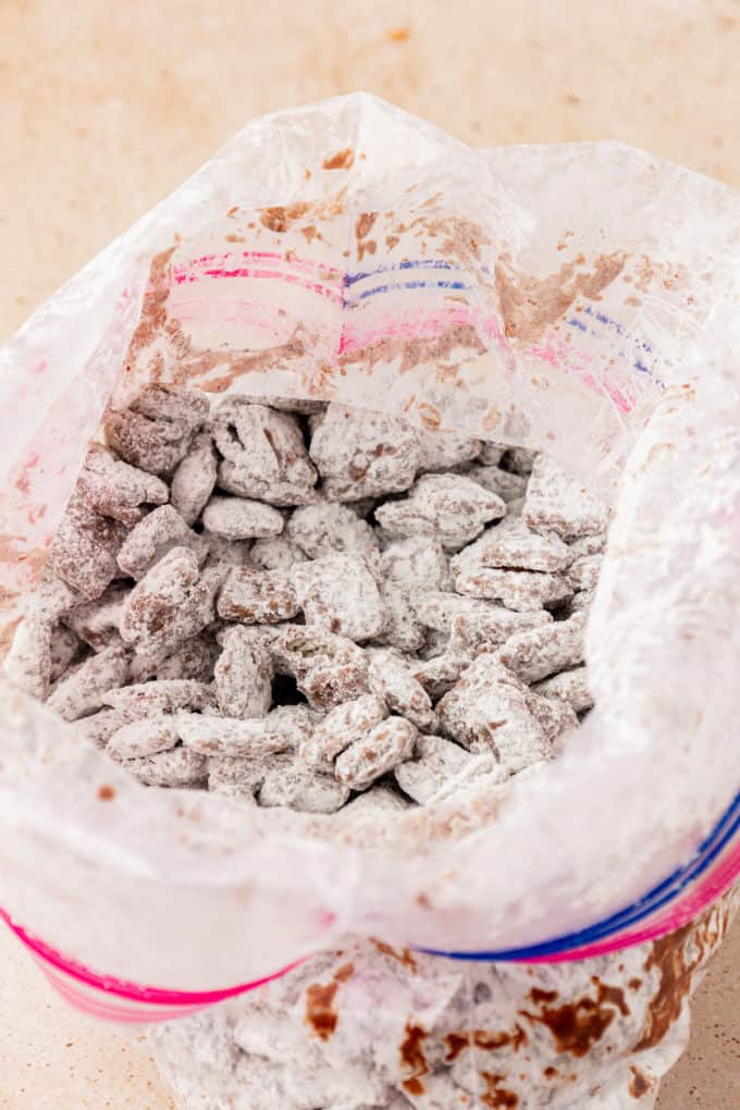 chex cereal coated in a chocolate mixture and powdered sugar in a large ziploc bag