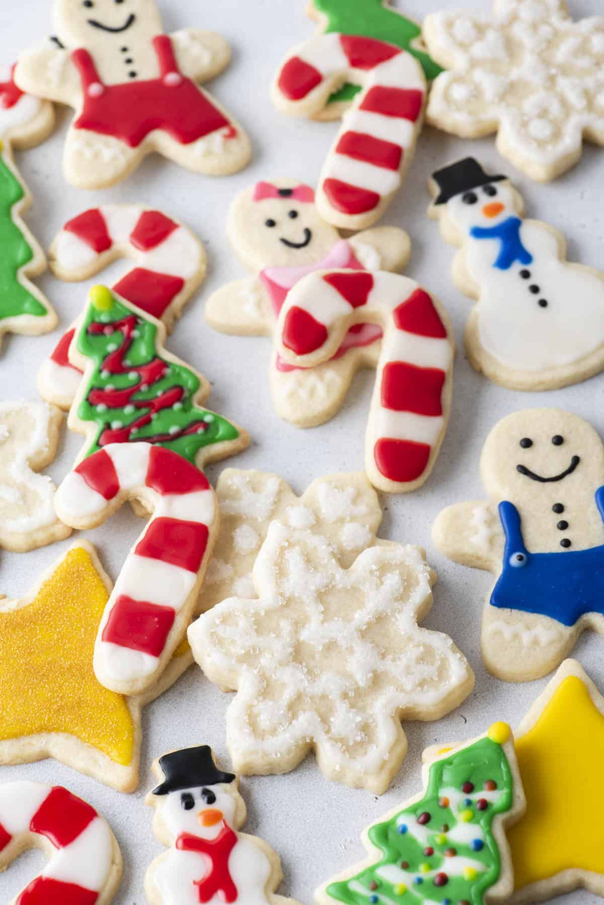 an assortment of christmas cookies decorated with royal icing scattered around each other including candy canes, christmas trees, snowmen, and snowflakes
