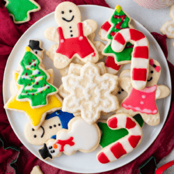 a collection of sugar cookies decorated with royal icing in christmas theme on a white plate
