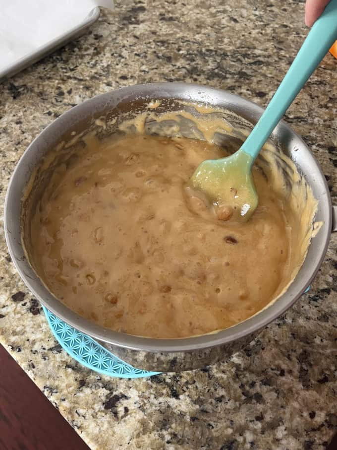 peanut brittle mixture in a pot on a counter top with a rubber spatula in it
