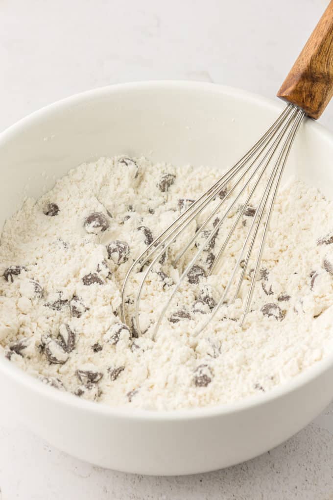 dry mix and chocolate chips being mixed with a whisk in a white bowl
