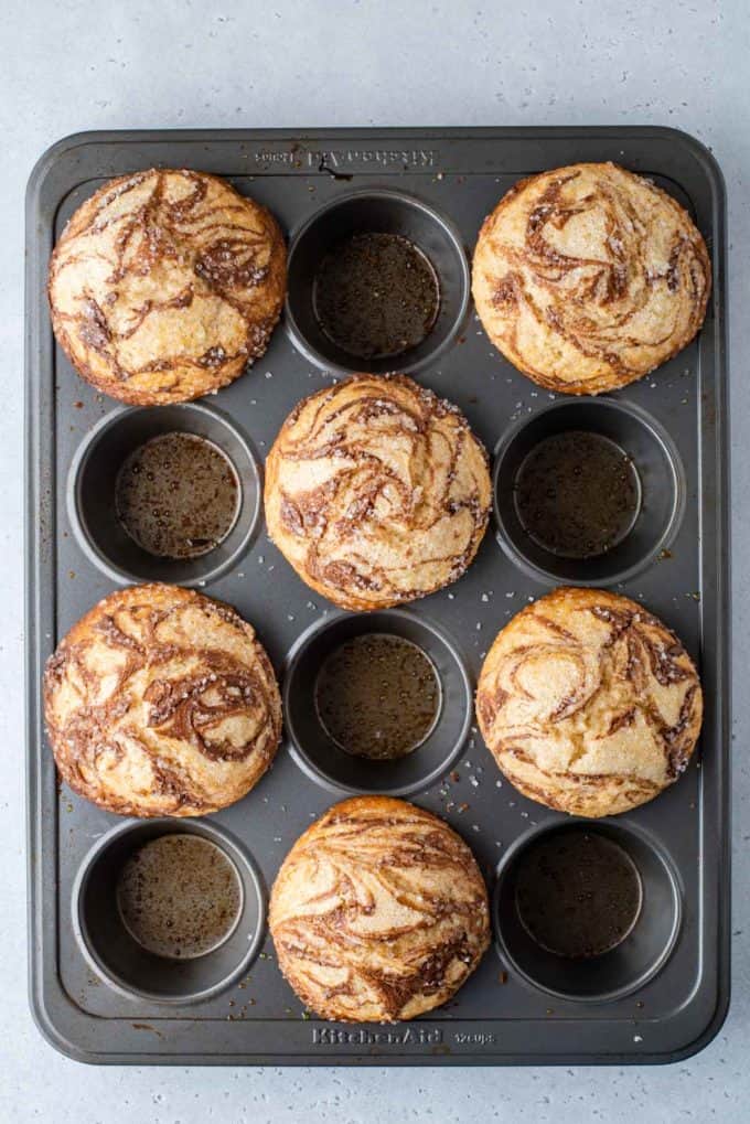 freshly baked nutella swirl muffins in a muffin pan, filling every other hole of the pan