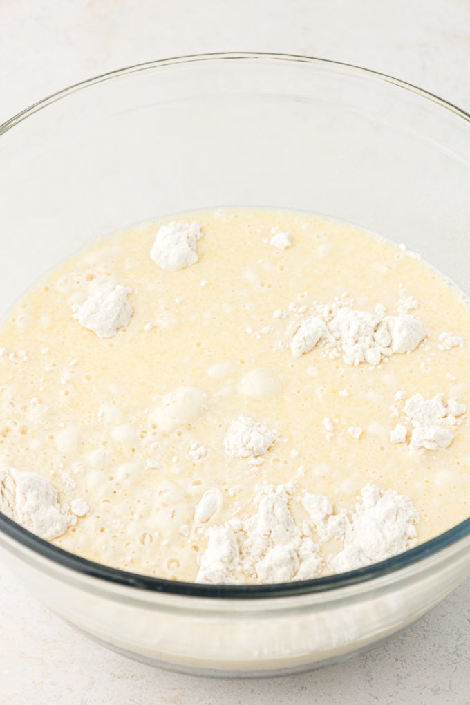 ingredients for sheet pan pancake batter in a clear glass bowl on a white surface