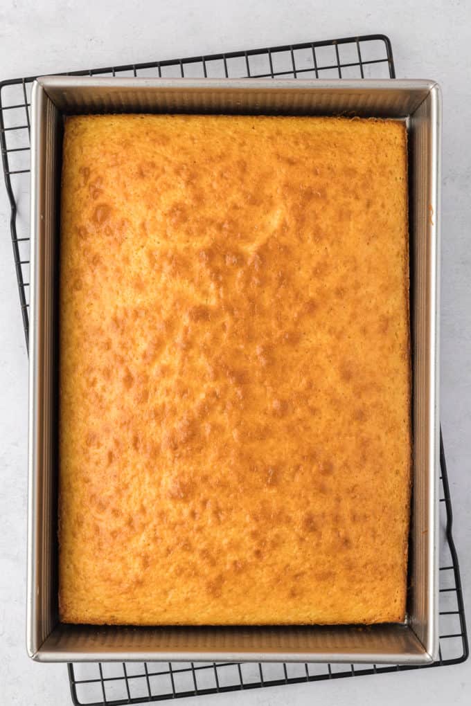 a freshly baked cake in a rectangular cake pan sitting on top of a wire rack