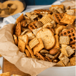 a white bowl lined with brown paper full of homemade chex mix