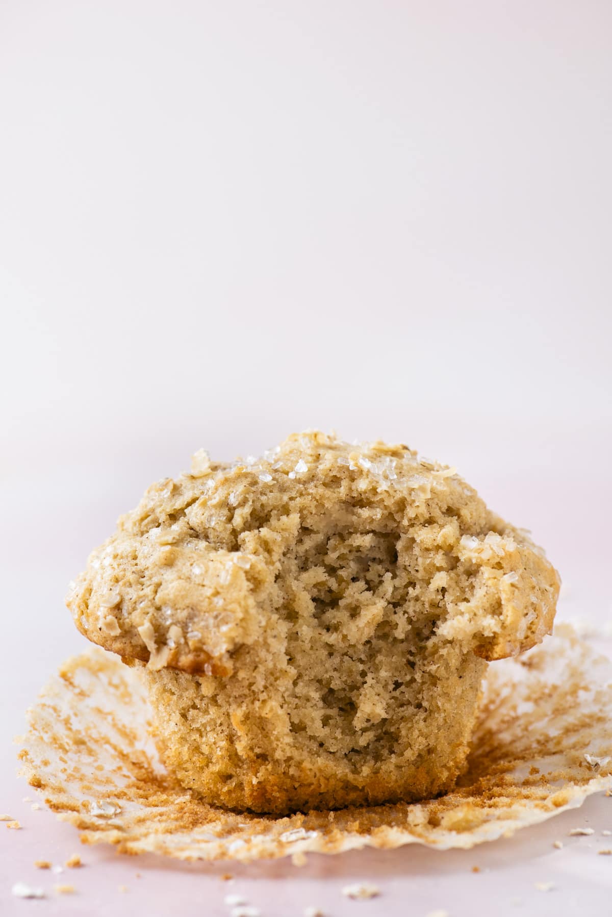 an oatmeal muffin with the muffin liner peeled away and a bite taken out