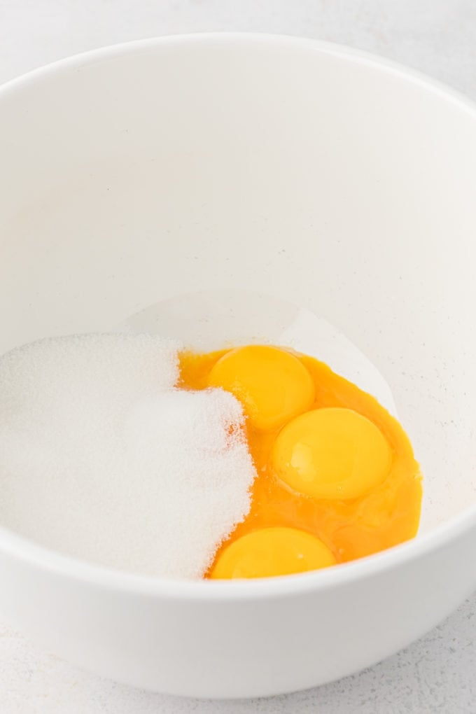a white bowl with egg yolks and sugar in it